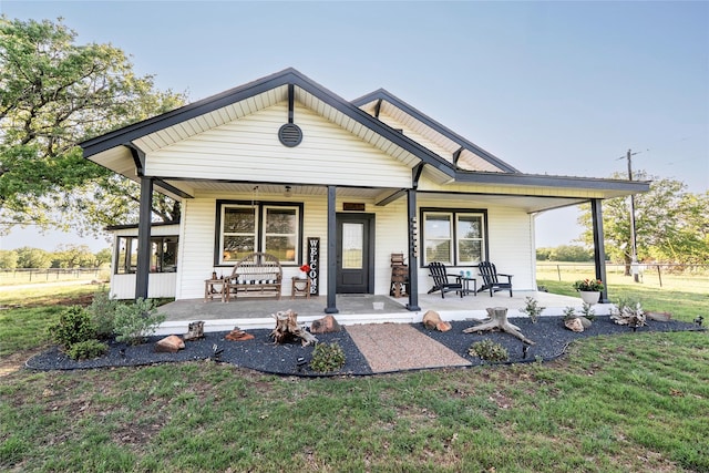 rear view of house featuring a yard, fence, and covered porch