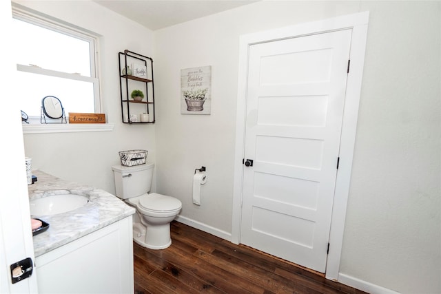 bathroom with wood-type flooring, toilet, baseboards, and vanity