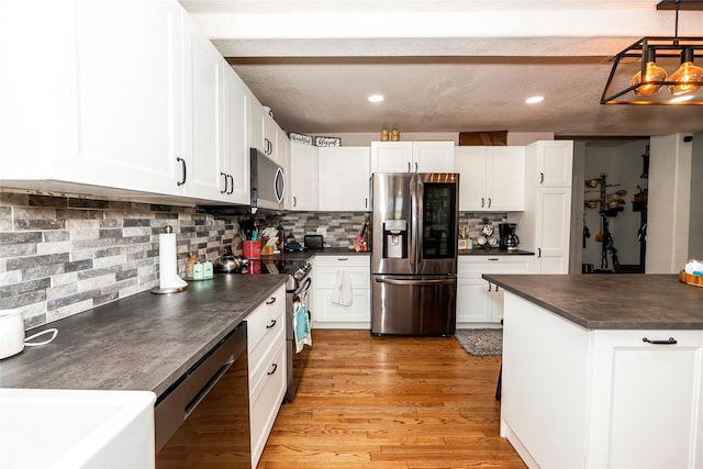 kitchen featuring dark countertops, appliances with stainless steel finishes, backsplash, and white cabinetry