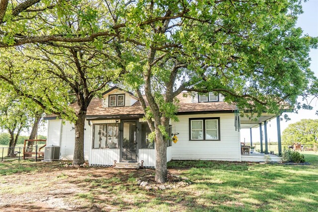 view of front of property featuring central air condition unit, fence, a sunroom, and a front yard