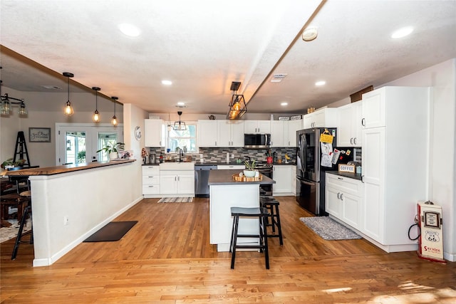 kitchen with dark countertops, a sink, stainless steel appliances, a kitchen bar, and backsplash