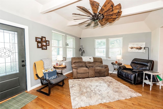living area featuring baseboards, lofted ceiling with beams, a wealth of natural light, and light wood-type flooring