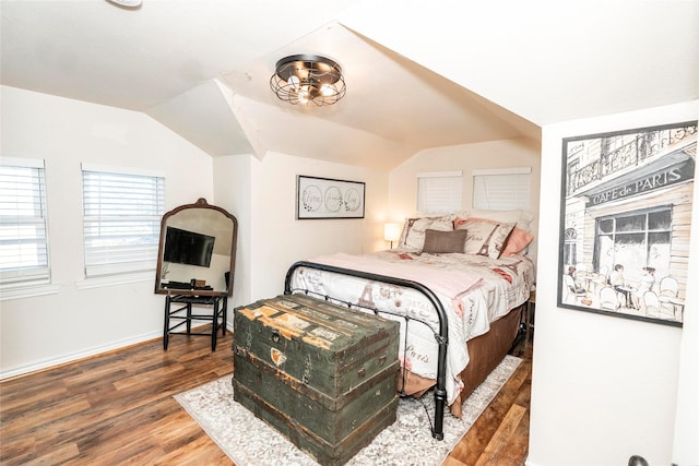 bedroom featuring baseboards, wood finished floors, and lofted ceiling