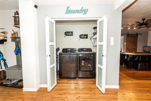 laundry room featuring washer and clothes dryer, light wood finished floors, ceiling fan, and a barn door