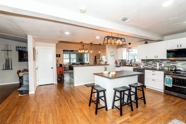 kitchen with a healthy amount of sunlight, dark countertops, stainless steel appliances, and visible vents