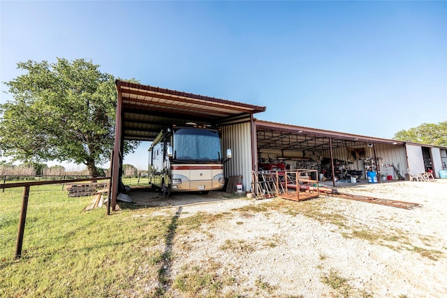 exterior space featuring fence, a detached carport, and an outbuilding