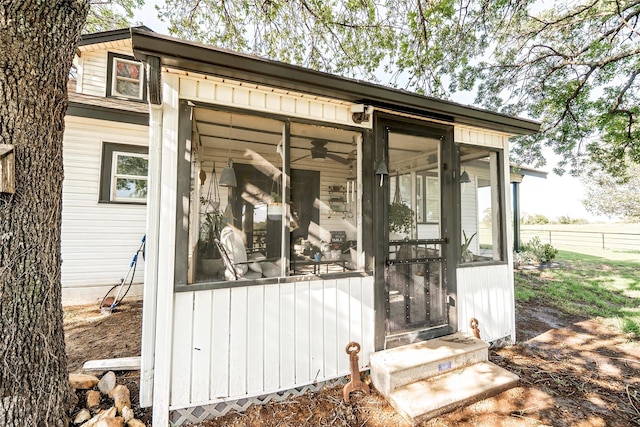 view of outbuilding with a sunroom, fence, and entry steps