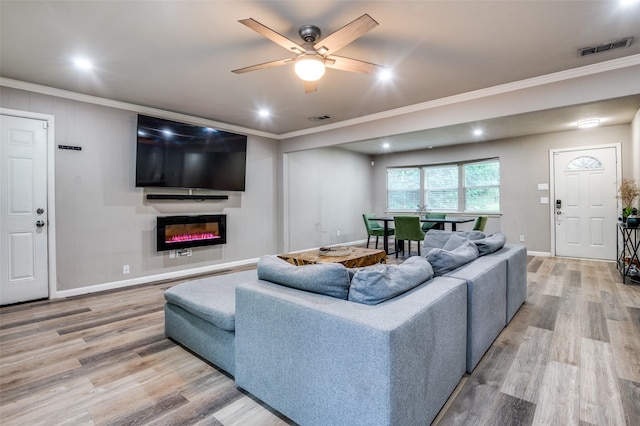 3467 Navajo Cir, Dallas, TX 75224 - living room with crown molding, light wood finished floors, a glass covered fireplace, ceiling fan, and recessed lighting