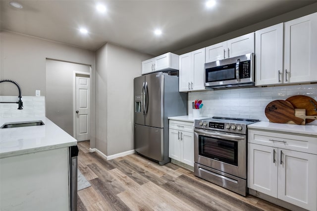 3467 Navajo Cir, Dallas, TX 75224 - kitchen with stainless steel appliances, recessed lighting, decorative backsplash, light wood-type flooring, and white cabinetry