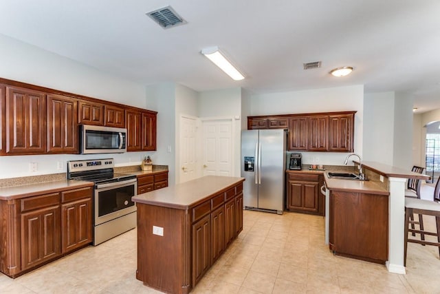 kitchen featuring a sink, a kitchen breakfast bar, stainless steel appliances, a peninsula, and visible vents