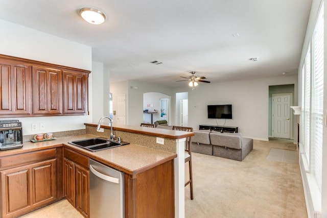 kitchen with a peninsula, light carpet, ceiling fan, a sink, and dishwasher