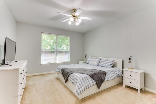 bedroom with baseboards, a ceiling fan, and light carpet