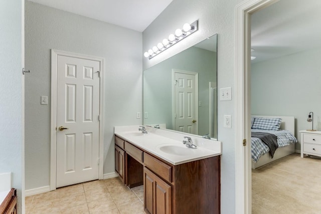 ensuite bathroom featuring a sink, tile patterned floors, and double vanity