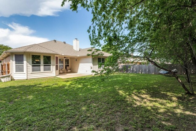 back of house featuring fence, a patio, a chimney, a ceiling fan, and a yard