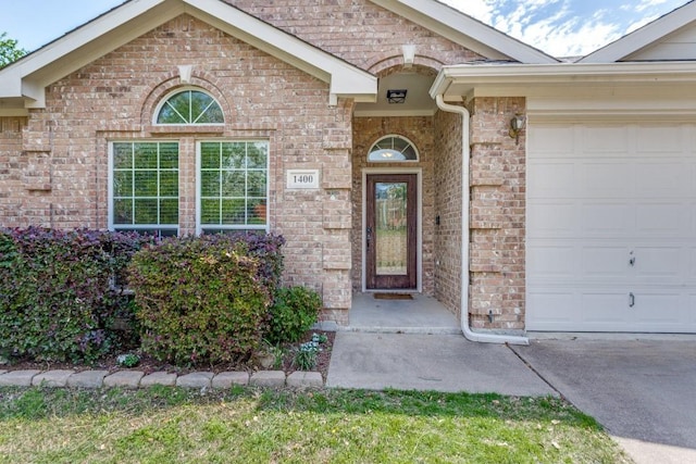 doorway to property with an attached garage and brick siding