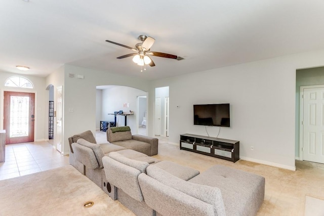 living area with light colored carpet, arched walkways, baseboards, and ceiling fan