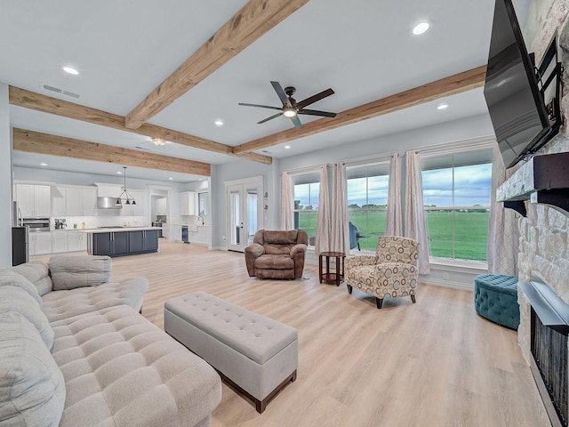 living room featuring recessed lighting, a wealth of natural light, beam ceiling, and a fireplace