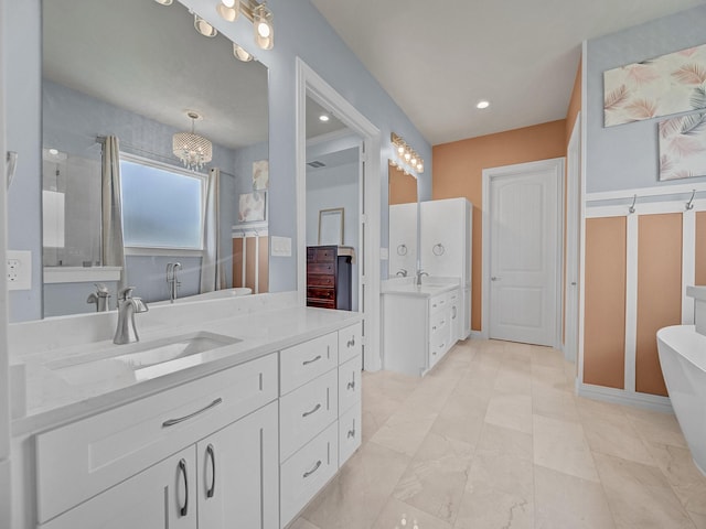 bathroom featuring a freestanding tub, two vanities, and a sink