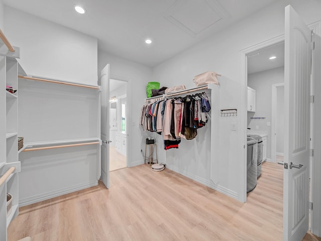 walk in closet with light wood-style floors and attic access