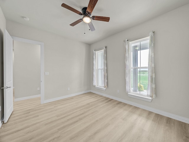 spare room featuring baseboards, a ceiling fan, and light wood-style flooring