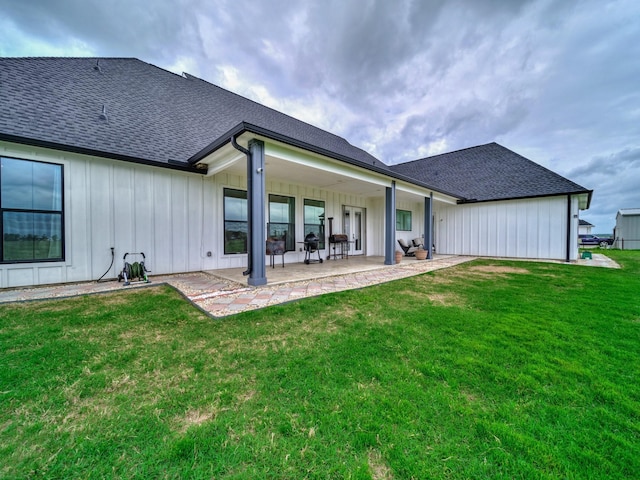rear view of property featuring board and batten siding, a lawn, and roof with shingles