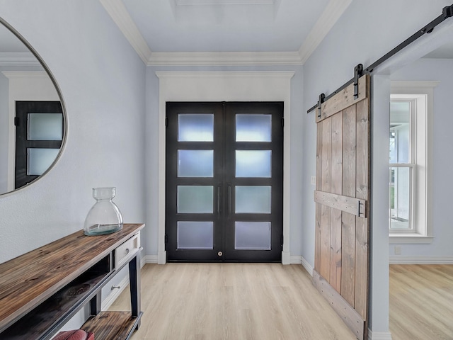 entryway featuring ornamental molding, a barn door, and light wood-style flooring