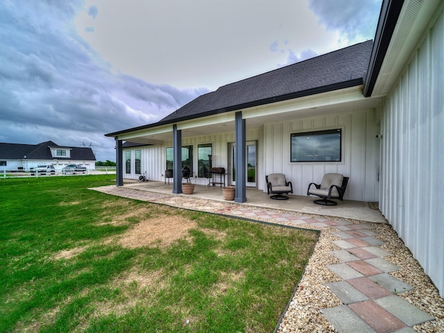 12530 Doyle Rd, Krum, TX 76249 - back of property with board and batten siding, a lawn, a shingled roof, and a patio area
