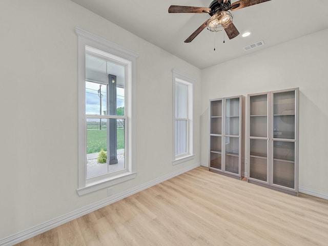 unfurnished room featuring baseboards, a ceiling fan, wood finished floors, and visible vents