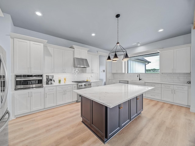 kitchen featuring white cabinets, a sink, stainless steel appliances, tasteful backsplash, and under cabinet range hood