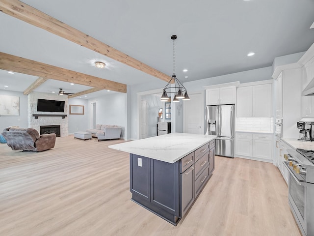 kitchen with beamed ceiling, open floor plan, light wood-type flooring, white cabinets, and appliances with stainless steel finishes