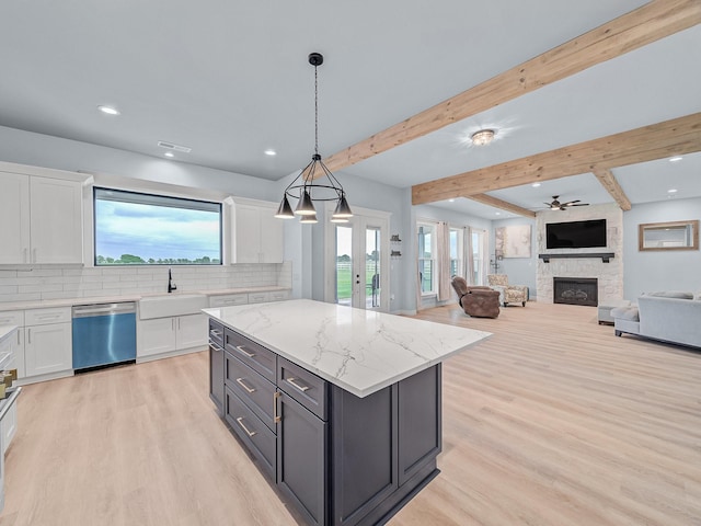 kitchen featuring a stone fireplace, light wood-type flooring, dishwasher, a sink, and white cabinetry