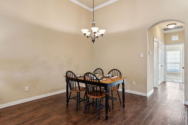 dining space with dark wood-style flooring, a notable chandelier, arched walkways, baseboards, and ornamental molding