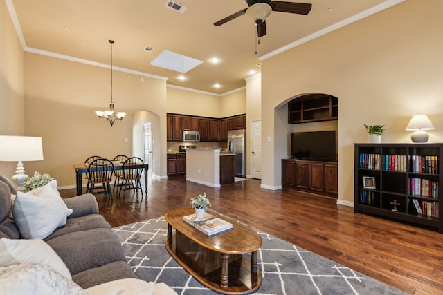 living area featuring visible vents, ornamental molding, dark wood-style floors, ceiling fan with notable chandelier, and a skylight