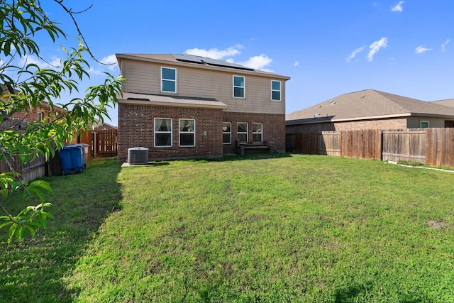 1320 Corkwood Dr, Princeton, TX 75407 - rear view of property featuring brick siding, roof mounted solar panels, a fenced backyard, central air condition unit, and a yard