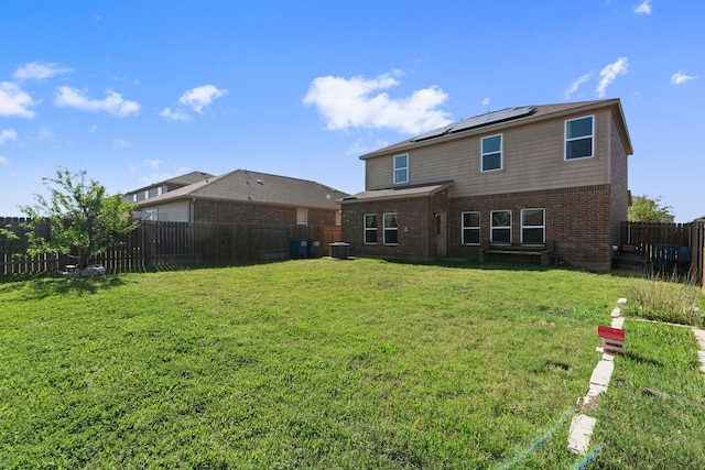 1320 Corkwood Dr, Princeton, TX 75407 - back of house with a fenced backyard, brick siding, central AC unit, roof mounted solar panels, and a yard