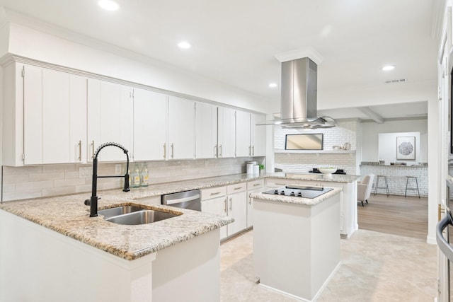 kitchen featuring backsplash, visible vents, island range hood, a sink, and a peninsula