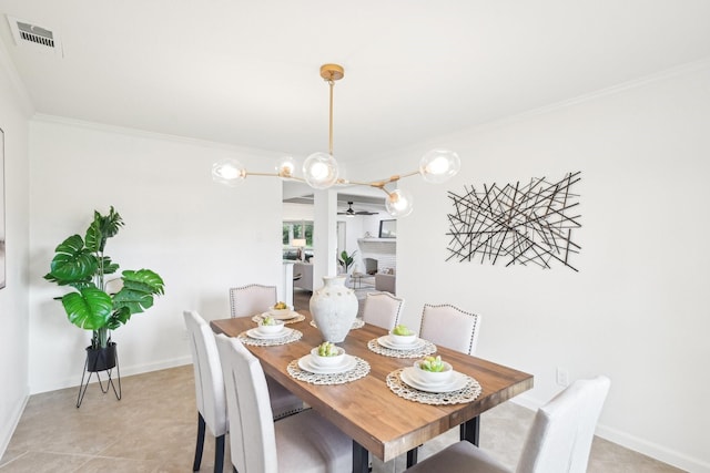 dining area featuring ceiling fan, a fireplace, baseboards, visible vents, and ornamental molding
