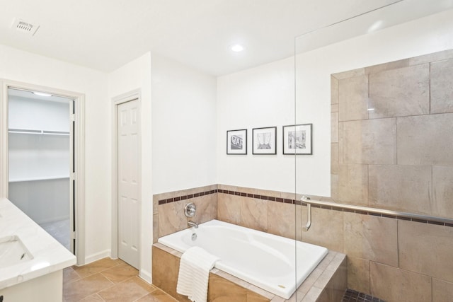 full bath featuring a garden tub, visible vents, tile patterned flooring, baseboards, and a spacious closet