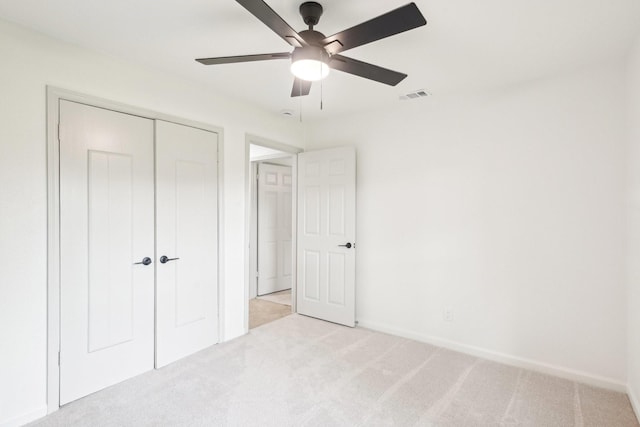 unfurnished bedroom featuring visible vents, a closet, baseboards, light colored carpet, and a ceiling fan