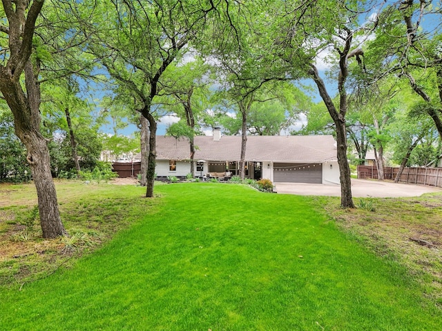 ranch-style house featuring a front lawn, fence, a chimney, an attached garage, and driveway
