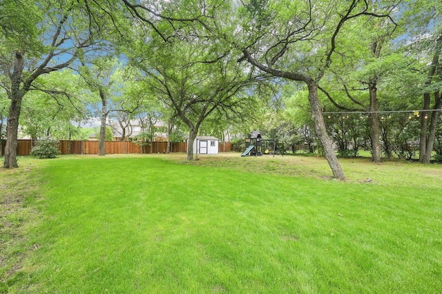 view of yard featuring a playground, an outbuilding, a fenced backyard, and a shed
