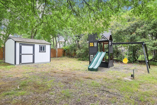 view of jungle gym with a storage unit, fence, and an outbuilding