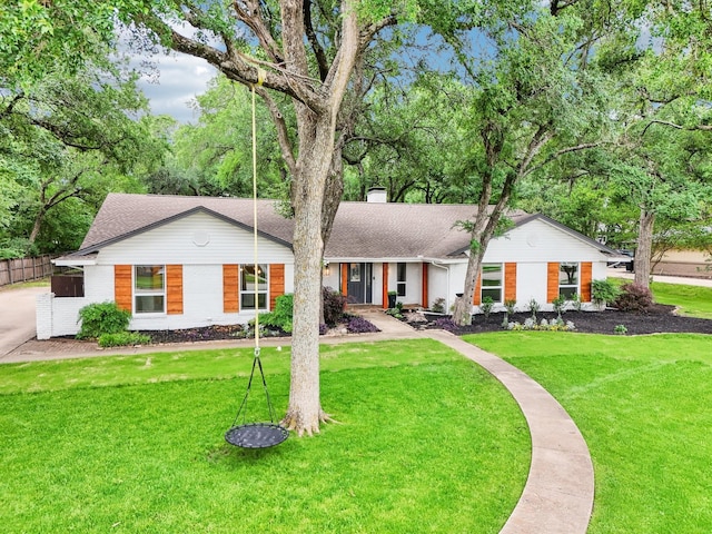 ranch-style home with brick siding, a chimney, a shingled roof, and a front yard