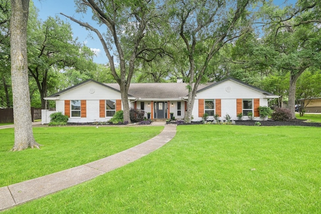 ranch-style house with fence, a chimney, a front lawn, and brick siding