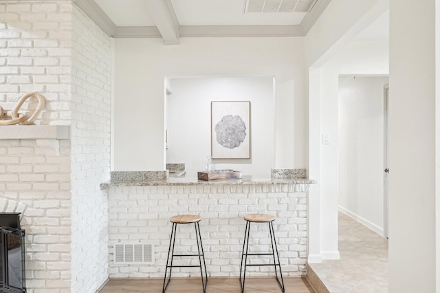 bar with visible vents, wood finished floors, a fireplace, and beamed ceiling