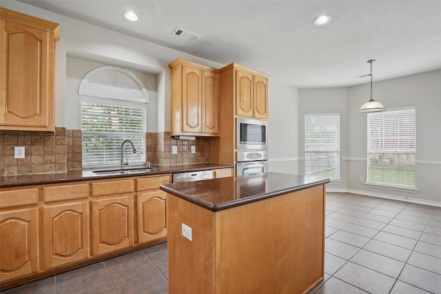 kitchen with a kitchen island, visible vents, a sink, dark tile patterned flooring, and stainless steel appliances