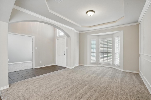 interior space with arched walkways, carpet, a tray ceiling, and a wealth of natural light