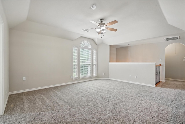 carpeted empty room featuring visible vents, a ceiling fan, arched walkways, and vaulted ceiling