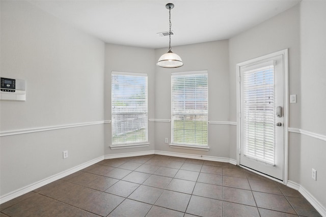 unfurnished dining area featuring baseboards, tile patterned floors, visible vents, and a wealth of natural light