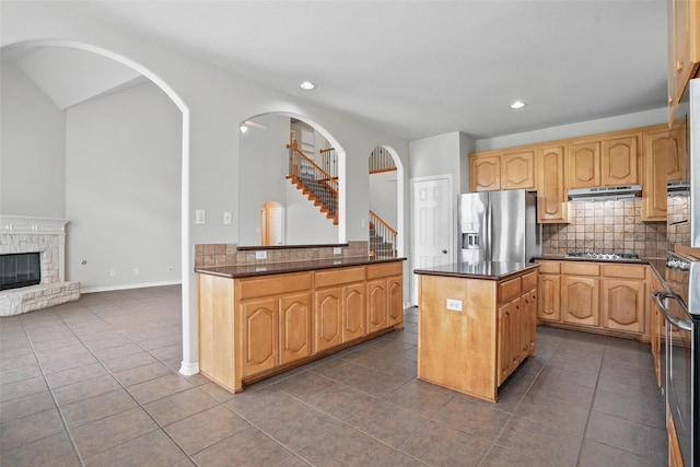 kitchen with dark tile patterned floors, decorative backsplash, stainless steel appliances, and under cabinet range hood